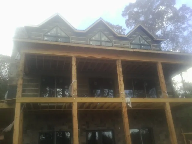 Dormers and porch framing on a large log home under construction — Roof Coating work by our crew in Unityville