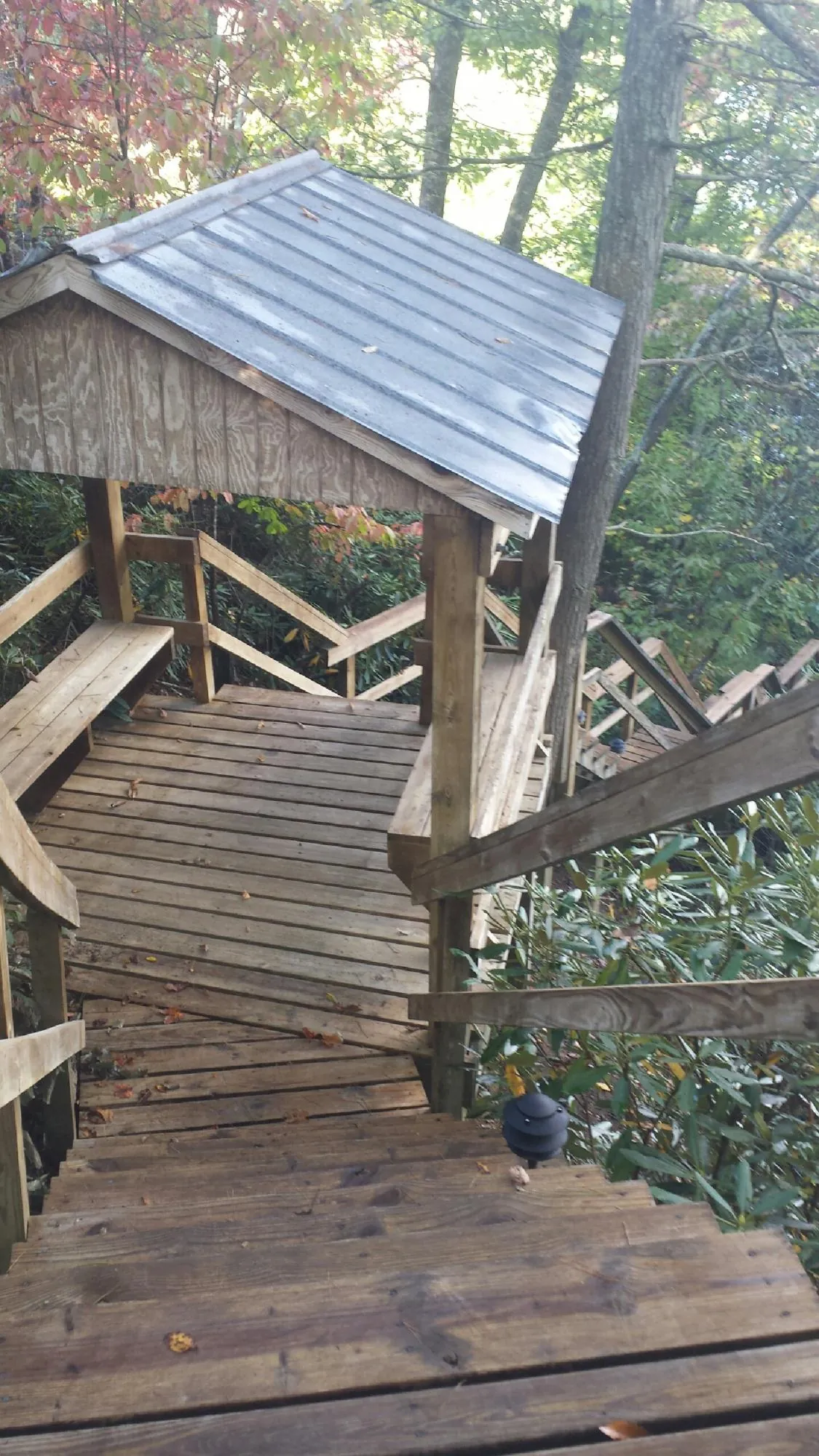 Metal roofed shelter over wooden steps on a wooded walkway — Skylight Repair & Installation work by our crew in Unityville