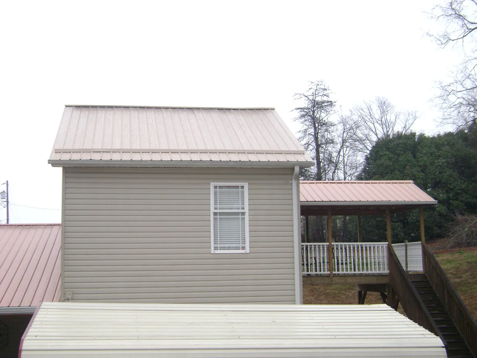 Tan metal roofs on a two story addition and attached porch, from a Roof Replacement job in Unityville